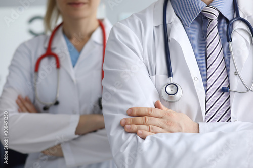 Man and woman doctors with phonendoscope around their necks stand with hands folded closeup. Work in private medical centers concept.