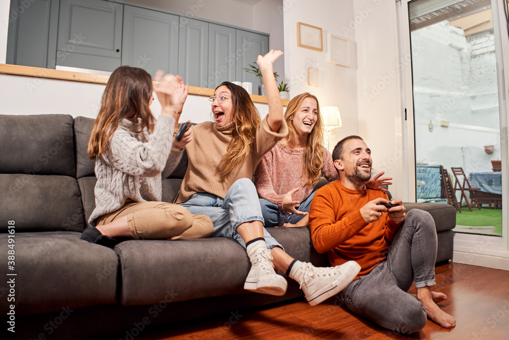 Group of friends sitting on sofa in living room and playing video games at home. Group of friends sitting on sofa in living room and playing video games at home.