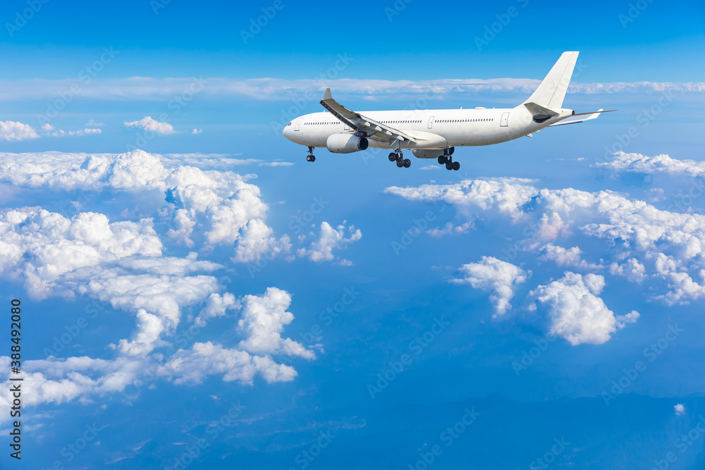 Fototapeta Samolot komercyjny lecący nad błękitne niebo i białe chmury.