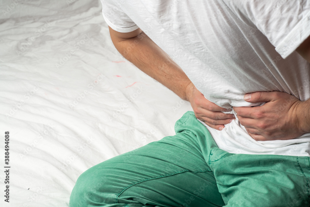 abdominal pain in an adult man. poisoning in a man. man holds his hands by the abdomen abdominal pain in an adult man. poisoning in a man. man holds his hands by the abdomen