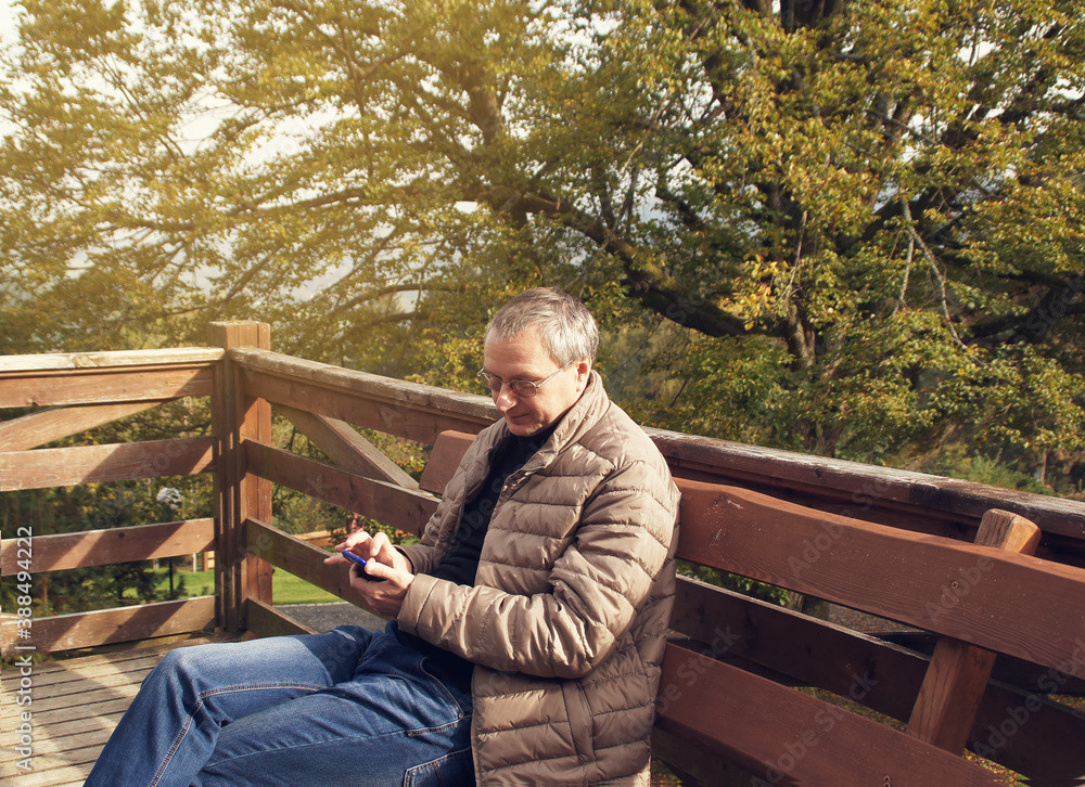 Fototapeta premium man holding a phone in the autumn forest 