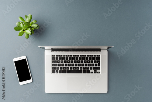 Office desktop with laptop and mobile phone on gray table. Business background. Flat lay