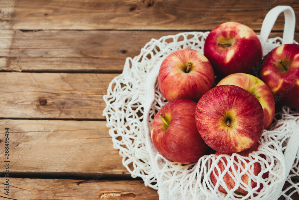 Varias manzanas dentro de una bolsa de rejilla con un fondo de madera Varias manzanas dentro de una bolsa de rejilla con un fondo de madera