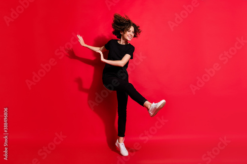 Photo portrait full body view of happy girl kicking dancing raising leg isolated on vivid red colored background