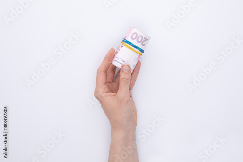 female hand holding roll of hryvnia banknotes isolated on white background, close view 