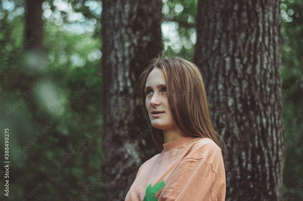 Upper body portrait of a young woman looking wondrous to the side in a forest Upper body portrait of a young woman looking wondrous to the side in a forest