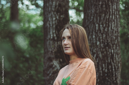 Upper body portrait of a young woman looking wondrous to the side in a forest