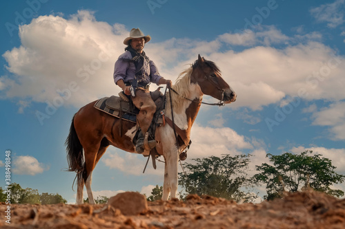 Silhouette and blur of action cowboy holding a gun on horseback.
