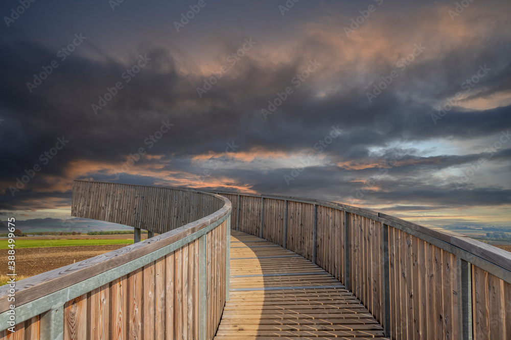 The wooden footbridge leading upwards serves as a lookout tower. In the background are dramatic clouds.
