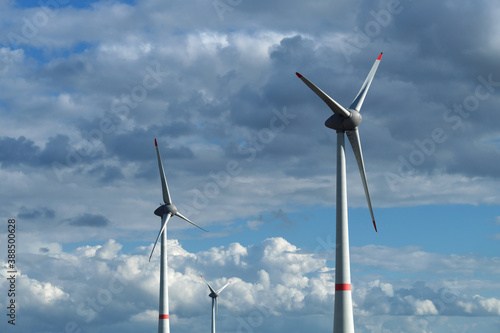 Wind turbines rising up into the sky with many clouds - Stockphoto