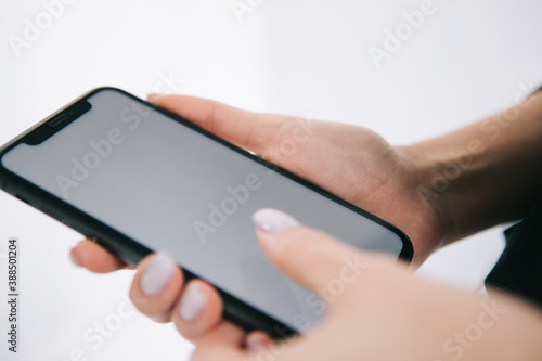 phone with a white screen in the hands of a girl with a manicure, copy space