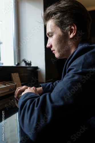 portrait of a young man sitting at the table. man in a jacket and a T-shirt © vetaka