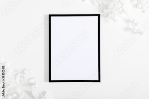 Christmas holiday composition. Xmas white decorations. White fir tree branches, berry, photo frame on white background. Christmas, New Year, winter concept. Flat lay, top view, copy space