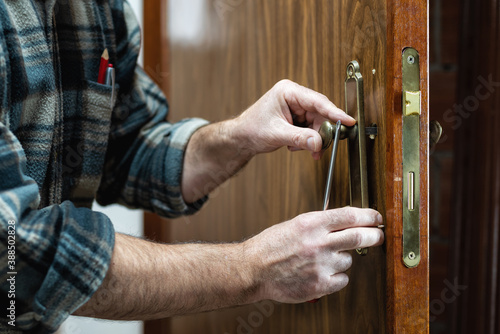 Close-up. Carpenter installs the lock handle of a wooden door. Construction industry. 