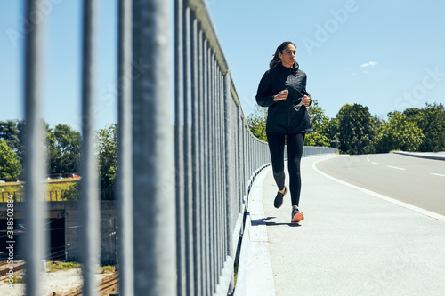 Full length of fit female runner running on the bridge.