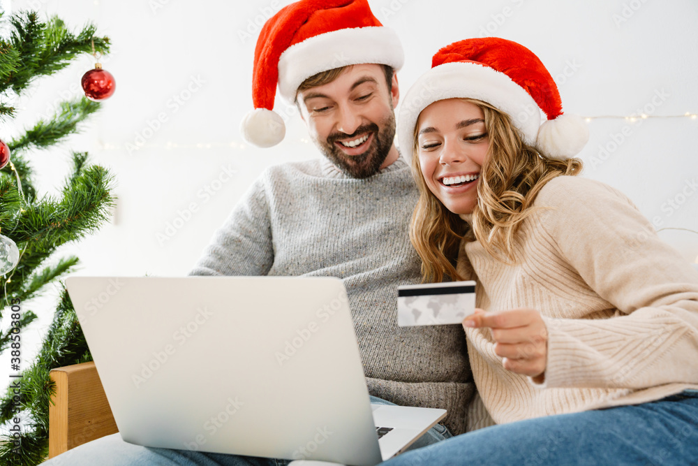 Caucasian happy couple using laptop and credit card while resting Caucasian happy couple using laptop and credit card while resting