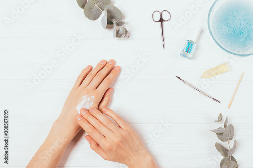 Flat lay home manicure process, woman's hands apply lotion