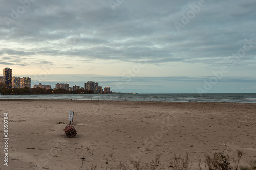 Epic shot of empty beach with highrise apartment buildings in distance with lights and cloudy sky