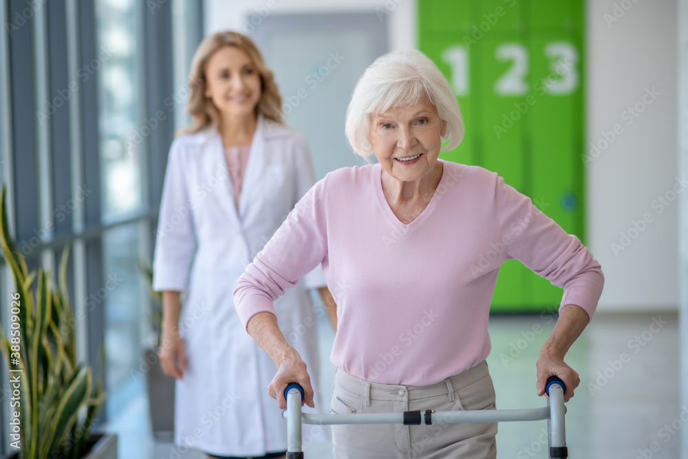 Obraz premium Senior woman with rolling-walker having rehabilitation procedures in clinic
