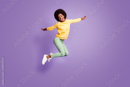 Fototapeta Naklejka Na Ścianę i Meble -  Full body photo of crazy afro american girl jump hold hands plane flying game concept isolated on violet color background