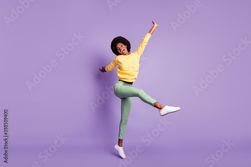 Fototapeta Naklejka Na Ścianę i Meble -  Full length photo of excited afro american girl jump wear yellow pullover green trousers isolated on violet color background
