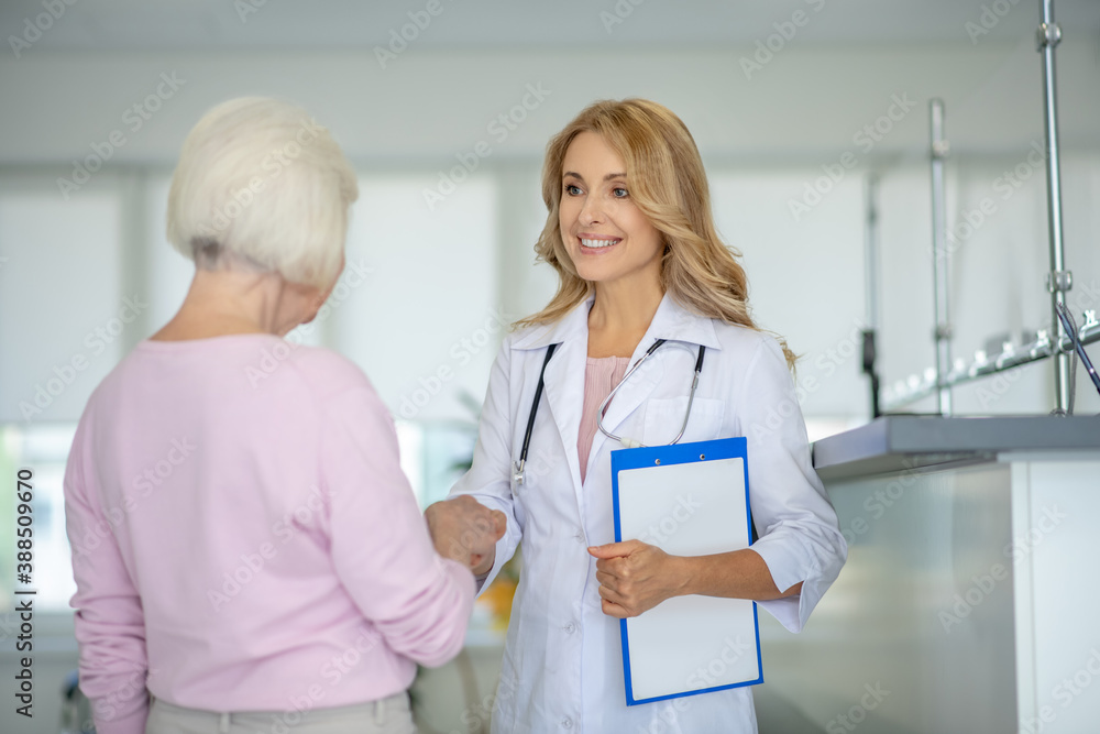 Senior woman talking to the doctor in the clinic corridor Senior woman talking to the doctor in the clinic corridor
