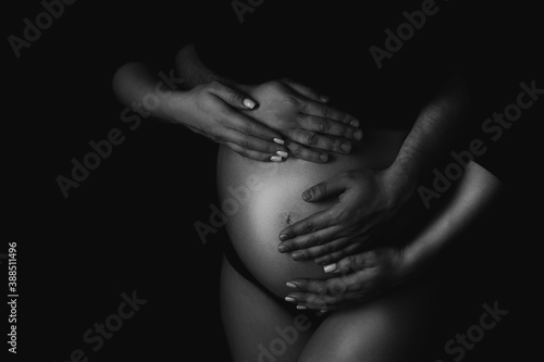 Male and female hands hug a pregnant woman. Black and white shooting photo