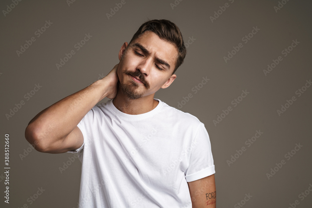 Obraz premium Image of tired handsome guy rubbing his neck while posing on camera