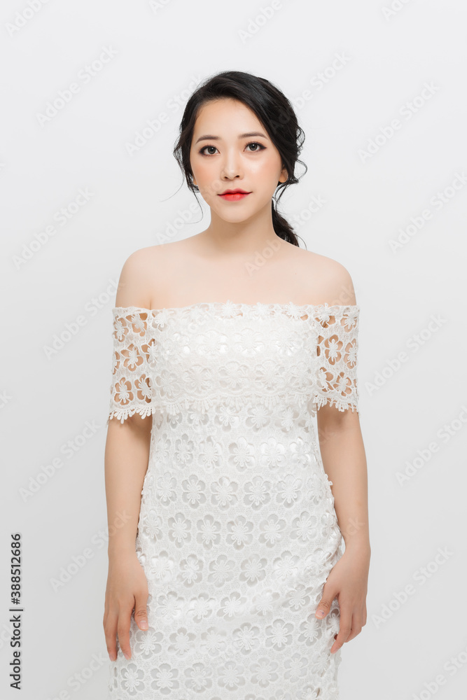 Beautiful young Asian woman with evening make-up wearing a white skinny dress over white background. Beautiful young Asian woman with evening make-up wearing a white skinny dress over white background.