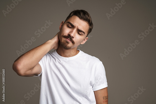 Image of tired handsome guy rubbing his neck while posing on camera