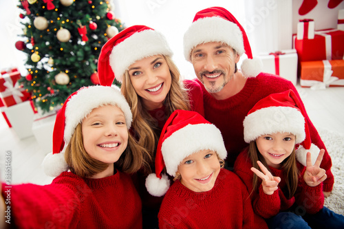 Photo of full big family five people meeting three little kids girl daughter show v-sign take shoot selfie wear x-mas headwear red jumper in home living room tree garland indoors