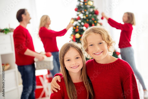 Photo of full big family five people gathering two small kids childhood embrace toothy smile parents sister decorate x-mas tree wear red jumper jeans in home living room indoors