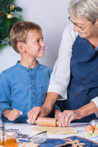 Grandmother with grandson cooking, kneading dough, baking in the kitchen
