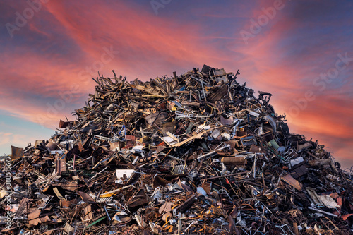 scrap metal heap at recycling junk yard against red sky at sunset photo