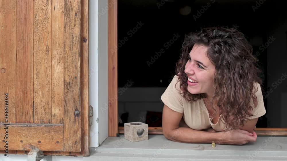 Young woman looking out the window and talking with some neighbour. Sharing, friendly concept Young woman looking out the window and talking with some neighbour. Sharing, friendly concept