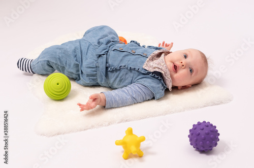 Portrait of a pretty baby girl is plaing with balls