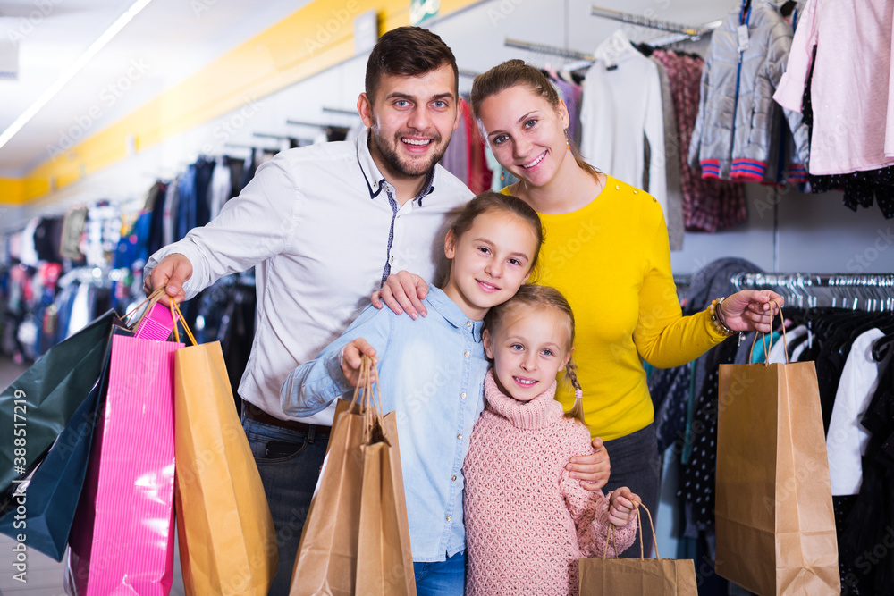happy friendly family of four with shopping bags in clothing shop