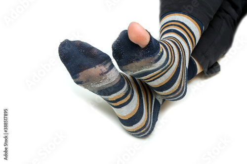 The feet with well worn striped socks isolated on a white background. One has a hole and a toe through it.  photo