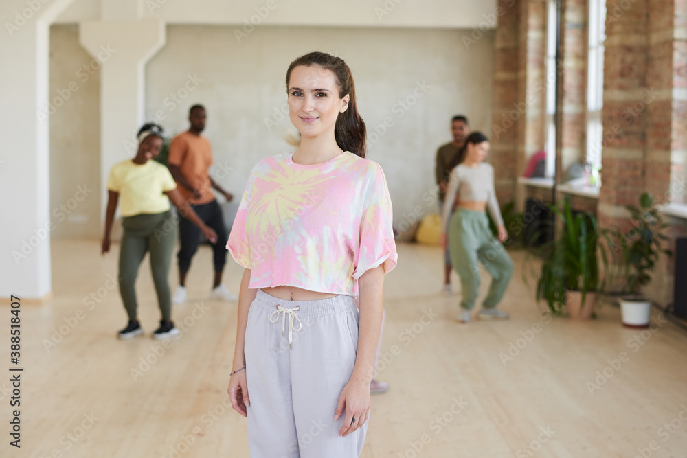 Naklejka premium Portrait of young woman looking at camera while dancing with other people in dance studio