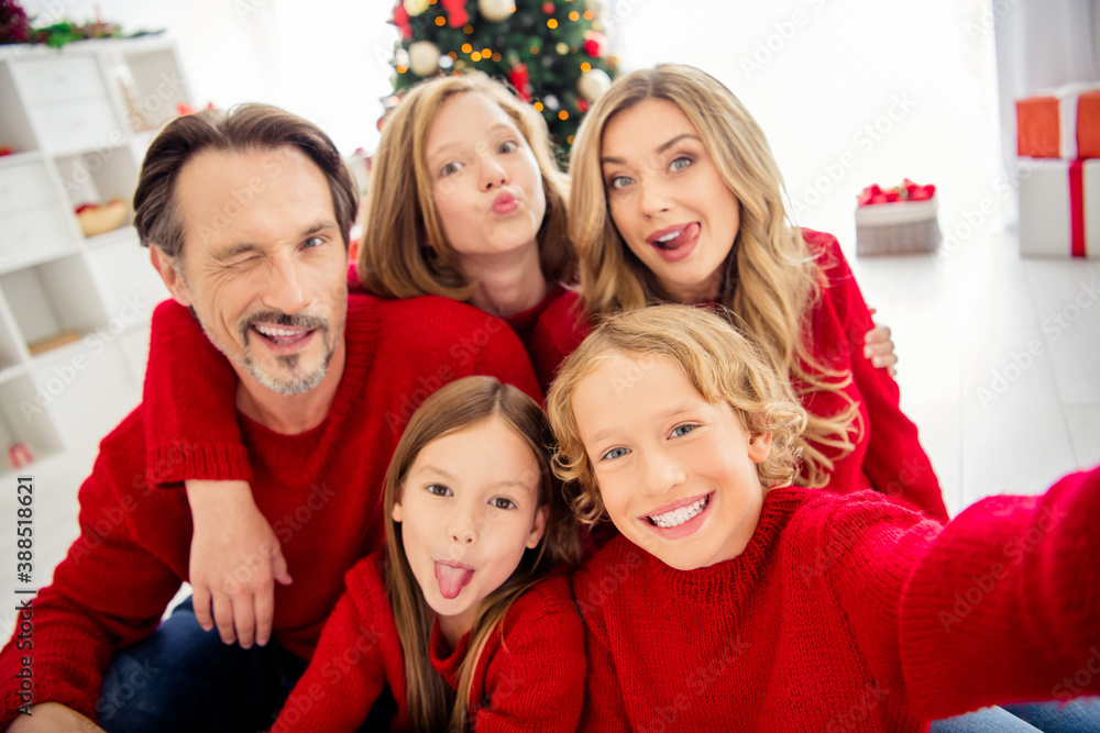 Closeup photo of full big family five people meeting three little kids cuddle tongue-out blink eye send air kiss wear red jumper in decorated living room x-mas tree garland indoors