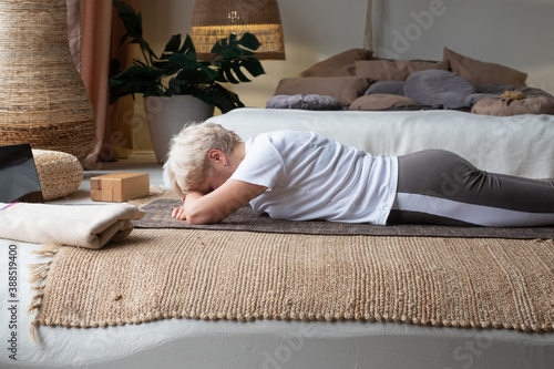 senior woman relaxes in yoga asana Makarasana or crocodile pose photo