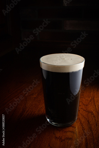 Vászonkép Glass of dark beer on wooden table