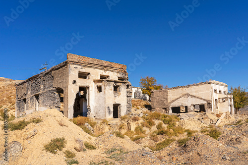 An old abandoned factory in the mountains. Fragments of destroyed buildings. Mountains.Ruins of a poly metal factory.Abandoned industrial production.The ruins of a mining and processing plant.Blue sky