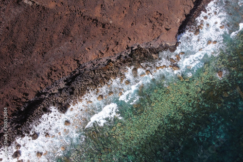 Aerial top view of waves splashing on rocky volcanic coastline. High quality photo
