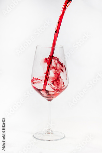 Red wine poured in a glass isolated on white.