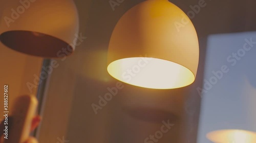 A woman's hand switching the light of a lamp on and off with the remote control