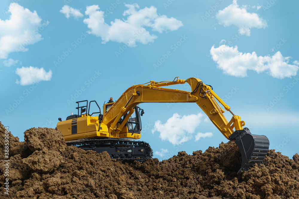 Yellow excavators are digging the soil in the construction site on the cloud and sky background Yellow excavators are digging the soil in the construction site on the cloud and sky background