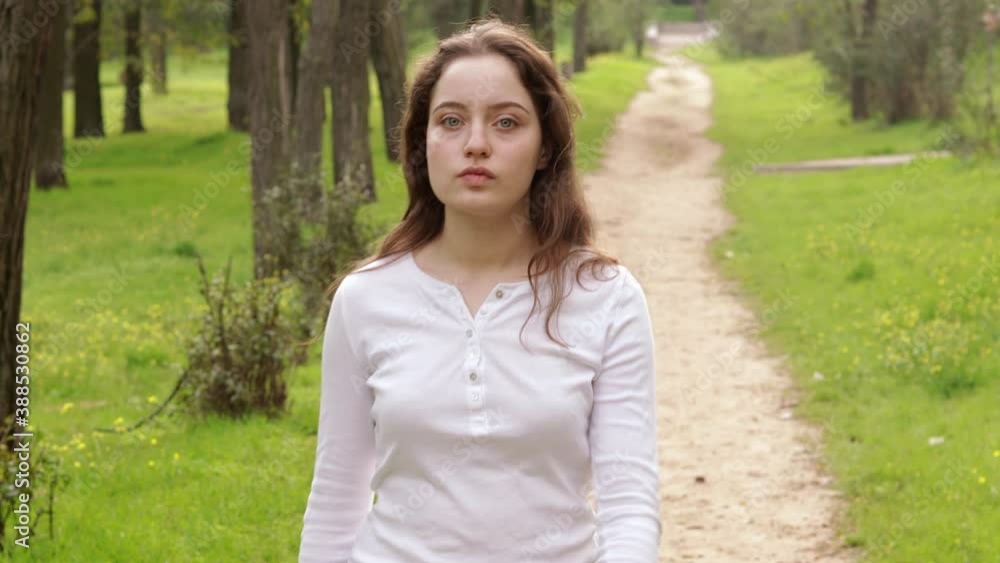 The girl walks along the park path and stops. Out of focus enters to the camera focus. The girl walks along the park path and stops. Out of focus enters to the camera focus.