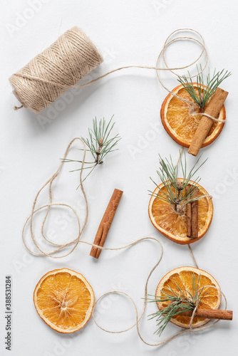 Homemade Christmas garland made from natural materials: dried oranges, pine branches, cinnamon and twine. Top view, flat lay, copy space