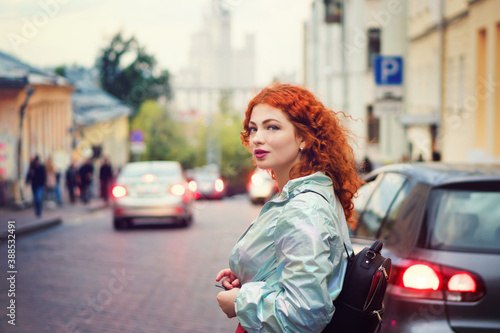 Romantic Curly Red-haired Girl Walking Through Town At Evening